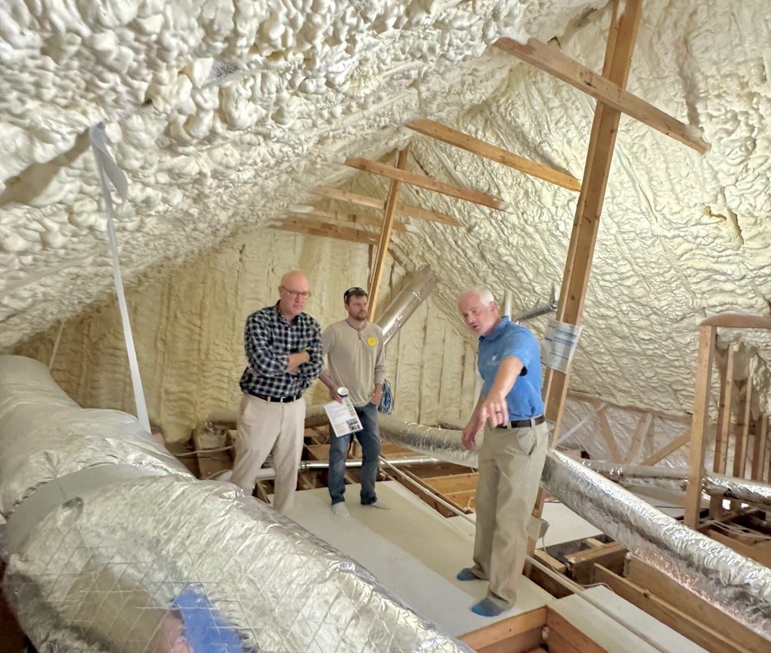 spray foam in attic with an E3 employee showing people around