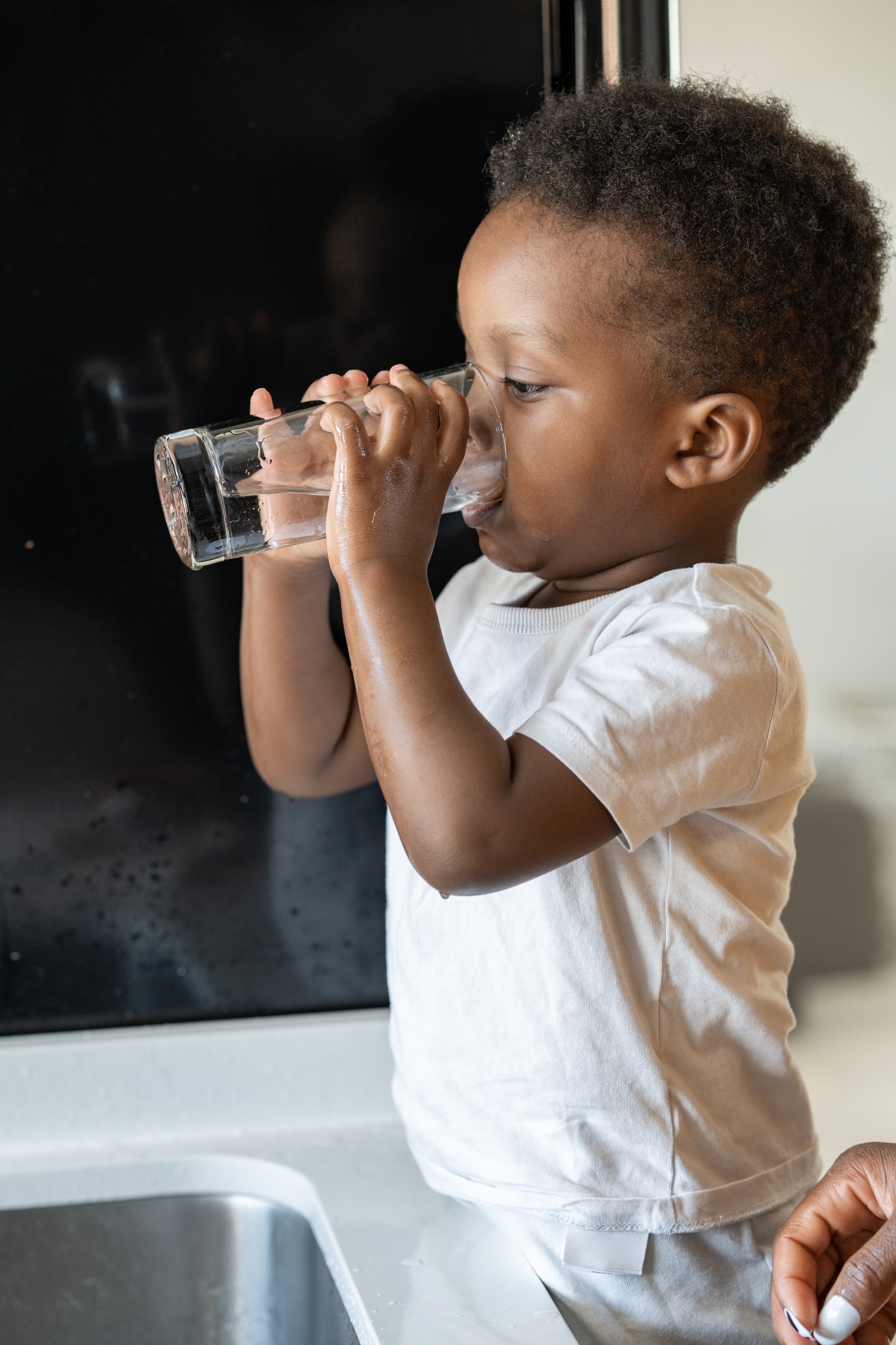 little boy drinking water out of a glass