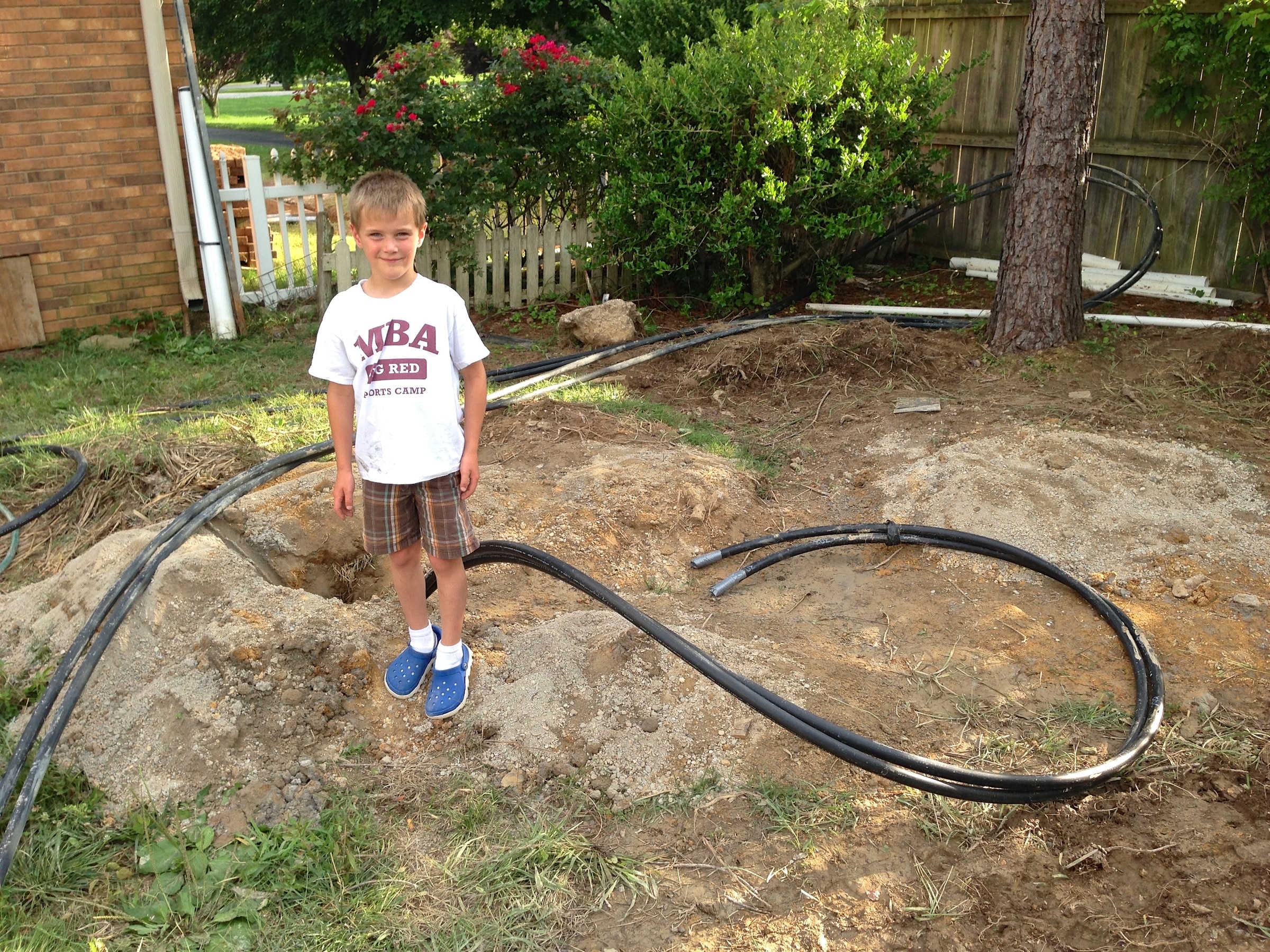 Kid standing with geothermal loops on the ground